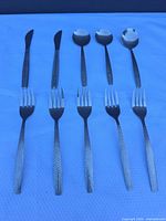 Full set laid out showing two knives, three spoons, five forks