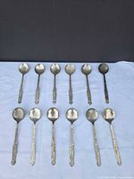 Full set of 12 matching dragon pattern spoons laid out