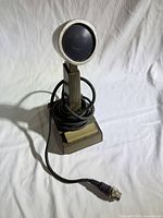 Front view of microphone on stand with coiled cable and 4-pin connector visible