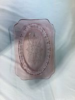 Top-down view of entire pink glass platter showing pressed floral design and border
