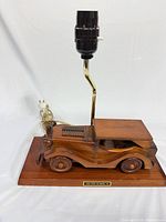 Front view showing carved wooden car on base with metal stem and socket