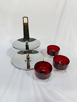 Full view of metal two-tier stand with wood handle and three red glass cups