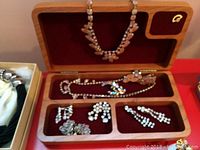 Wood jewelry box open showing velvet tray with rhinestone necklaces and earrings; white and navy presentation boxes visible at sides