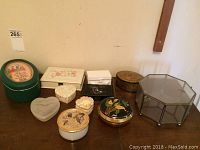 Table displaying nine assorted trinket boxes with different shapes, colors, and designs.