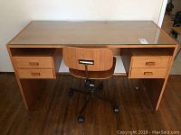Front view of teak desk with glass top and chair in front