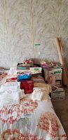 Wide view of all items arranged on a bed and boxes with some rolls of fabric or paper against the wall