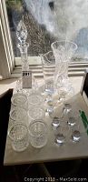 Full set of crystal barware on a table, including decanter, pitcher, vase, tumblers, and stemmed glasses