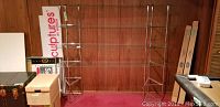 Full view of the larger and smaller glass shelving units against wood paneling