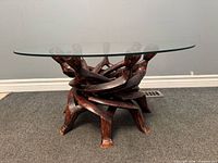 Full view of table showing carved wood base and glass top