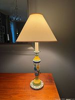 Full view of lit lamp with shade on wooden surface