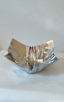 Angled view of stainless steel bowl showing crumpled square form