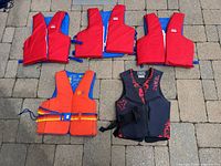 Group shot of six life jackets laid on patio