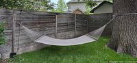 Hammock hung between fence and tree showing full width and net body