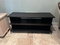 Front view of dark brown TV stand showing open shelves and casters