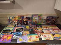 Overview shot of approximately 75 children’s books laid out in three rows showing covers and variety of formats