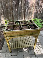 Front angle of wooden raised planter showing compartments and soil