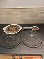 All four pieces arranged on countertop: two glass bowls, one ceramic trivet/plate, one ceramic spoon rest