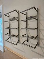 Pair of identical brushed nickel stainless steel 4-tier towel racks mounted on wall