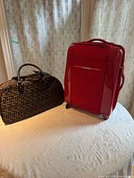 Overall view of both bags: red rolling suitcase and patterned duffel
