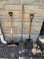 Front view of all three shovels leaning against wall