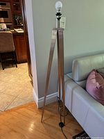 Full view of brushed nickel tripod floor lamp beside sofa