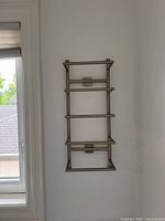 Full view of four-tier brushed nickel towel rack mounted on wall