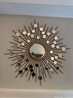 Front view of sunburst wall mirror showing central mirror, spokes, and multiple small mirrored discs