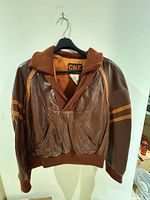 Front view of CNF brown leather pullover jacket showing knit collar, cuffs, waistband and sleeve stripes