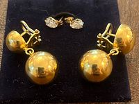 Dangle clip-on ball earrings and stud crystal earrings on display pad