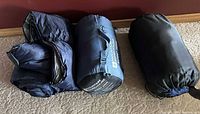Three rolled/packed sleeping bags on floor