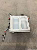 Folded white plastic gate with twin translucent panels alongside handles and hardware visible