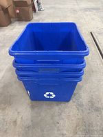 Stacked blue plastic recycling bins front view, white symbol visible