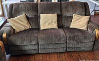 Front view of brown/tan three-seat reclining sofa with pillows
