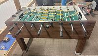 Full view of foosball table showing cabinet, legs, rods, players