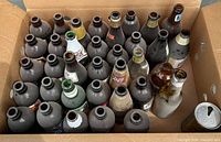 Box containing roughly thirty empty glass beer bottles of mixed colors