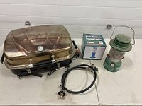 Overall lot showing grill, hose, boxed lantern and Coleman lantern