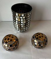 Tall cylindrical vase and two round votive holders displayed together