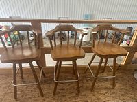 Front view of all three honey oak bar stools on raised platform