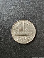 Reverse of 1951 Canada 5 cents coin showing refinery design and maple leaves