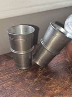 Both pewter shot glasses standing on wooden surface