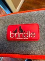 Close-up of Brindle logo patch on gray and orange pet bed