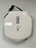 Closed white George Foreman grill showing overall form and cord