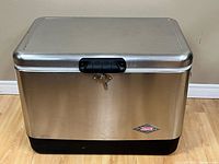 Front view of stainless Coleman cooler showing latch and badge