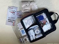Open first aid kit with gauze, bandages, gloves, CPR face shield boxes and scissors