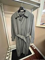 Front view of London Fog trench coat on hanger, showing belt and lapels