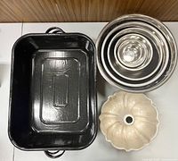 Top view showing one black enamel roasting pan, nested stainless bowls, Bundt pan