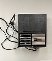 Top view showing full projector body, front grill with logo, attached power cord