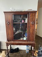 Front view of china cabinet showing glass door, rosettes, and legs
