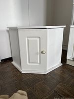 Front view of one white corner cabinet closed