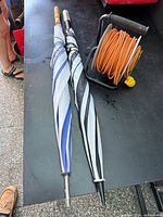 Two closed umbrellas and cord reel on table